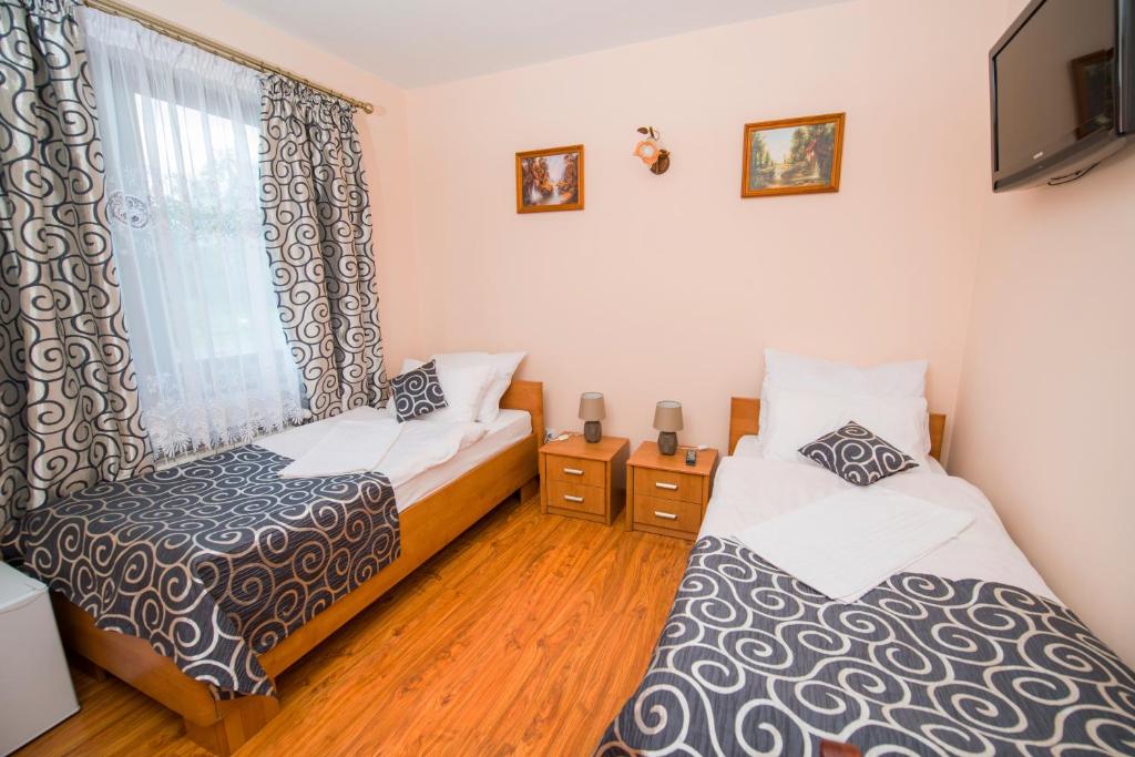 2 Betten in einem kleinen Zimmer mit Fenster in der Unterkunft Nad Bugiem in Hrubieszów
