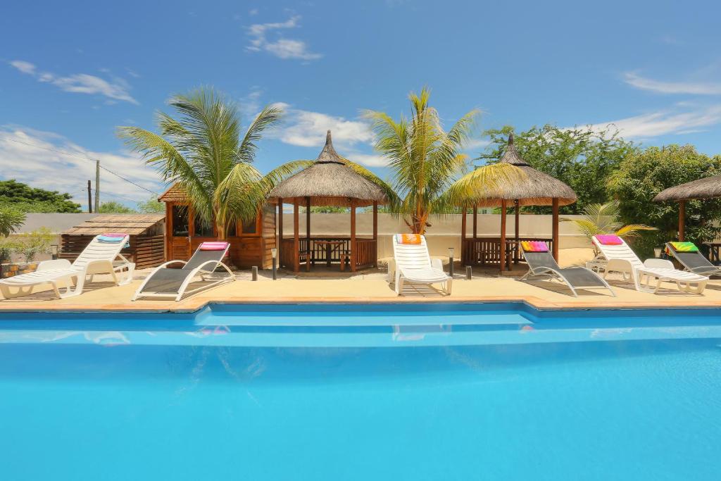 a pool with chairs and tables and a pavilion at L'Oiseau de L'Ocean Tourist Residence in Flic-en-Flac