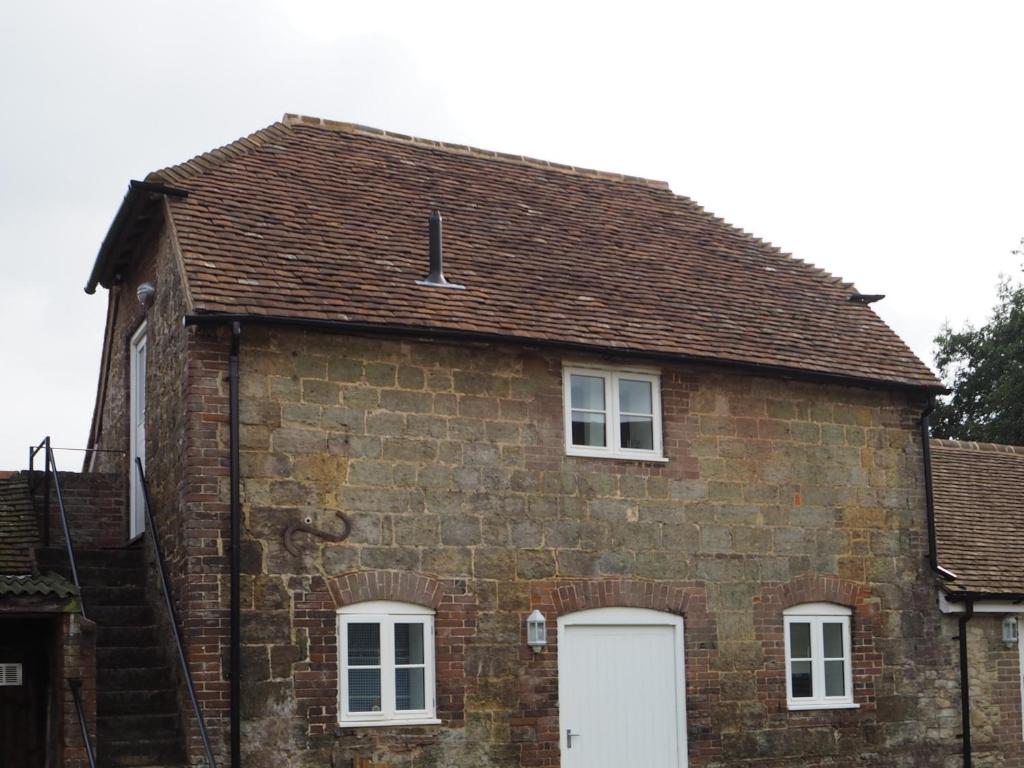 una vieja casa de ladrillo con una puerta blanca en Hayloft en Pulborough