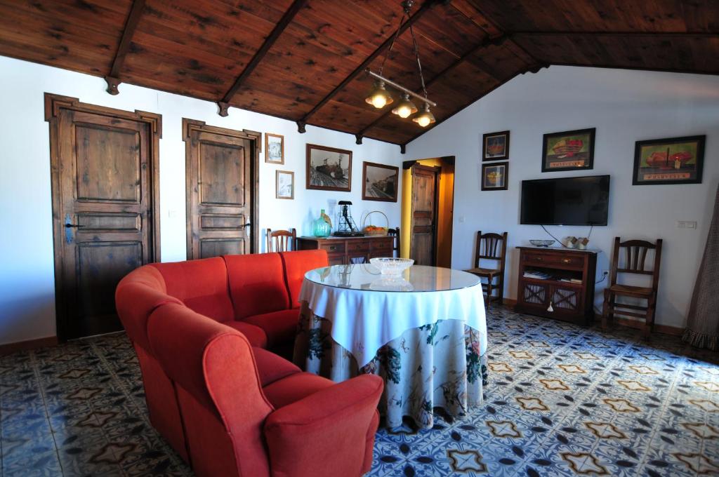 ein Wohnzimmer mit einem roten Sofa und einem Tisch in der Unterkunft El Romerito in Zalamea la Real