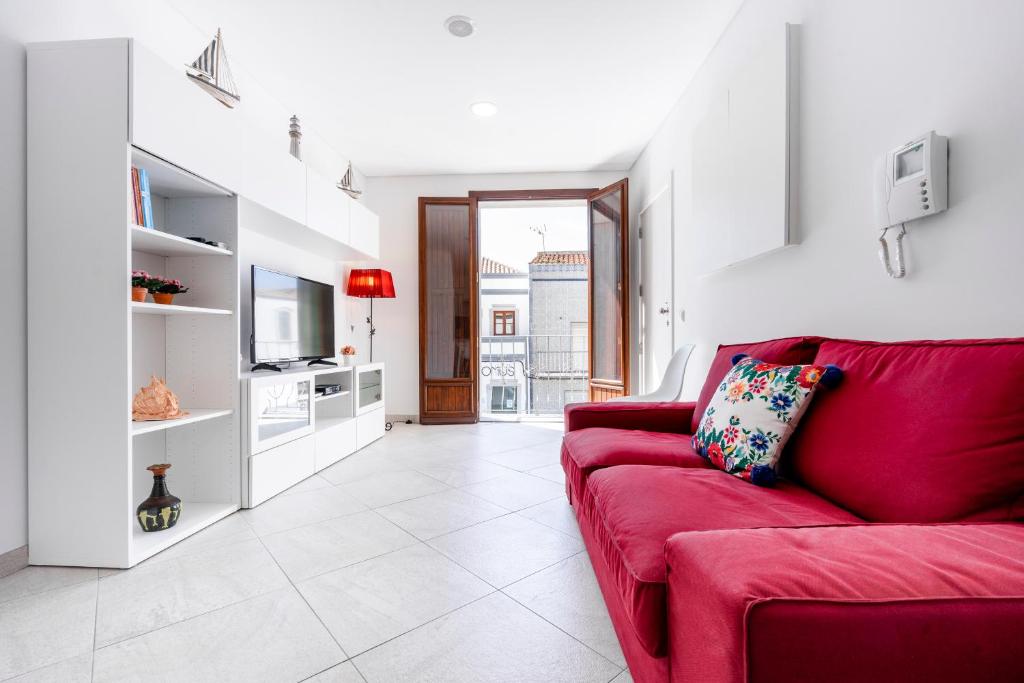 a living room with a red couch and a tv at Apartamento 1º de Maio in Tavira