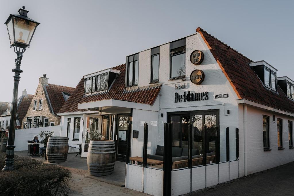 a white building with a restaurant with a street light at Hotel De4dames in Schiermonnikoog