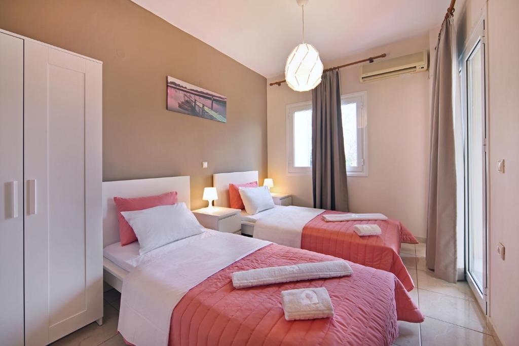 a hotel room with two beds and a window at Omega Comfy Apartments Almyrida in Almyrida