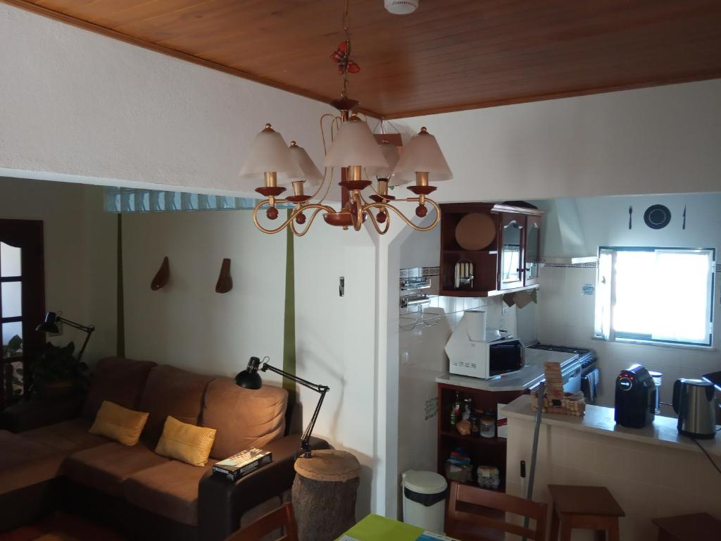 a living room with a couch and a chandelier at Hostel Nature in Zambujeira do Mar