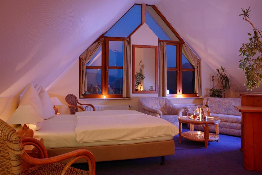 a bedroom with a bed and a couch and windows at Logis Hotel-Restaurant Petry in Vianden