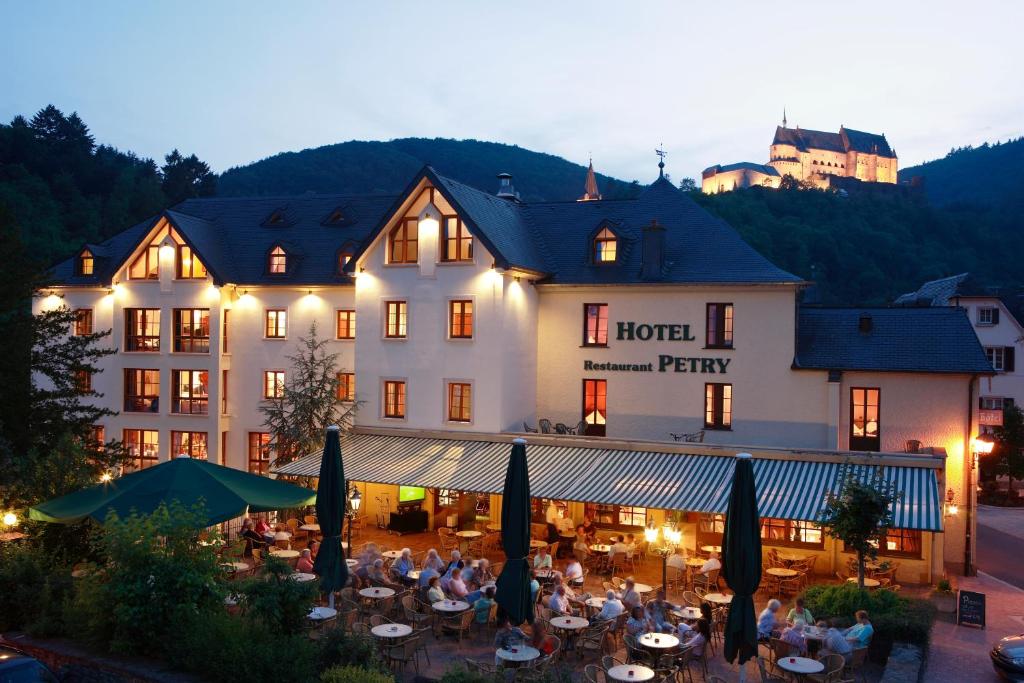 um hotel com pessoas sentadas em mesas à frente dele em Logis Hotel-Restaurant Petry em Vianden