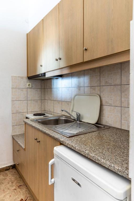 a kitchen with a sink and wooden cabinets at Dimitra's Studios in Stoupa