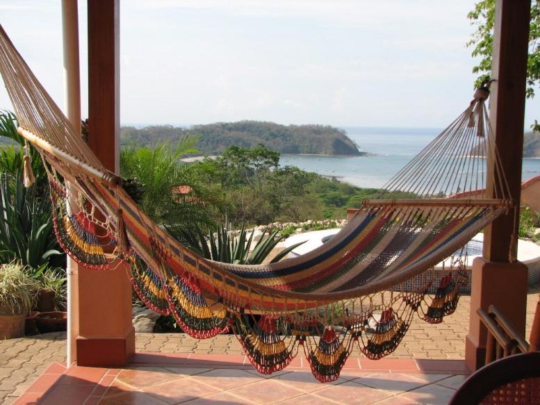 a hammock hanging from a porch with a view of the ocean at Beautifull Casa Pastor in Sámara