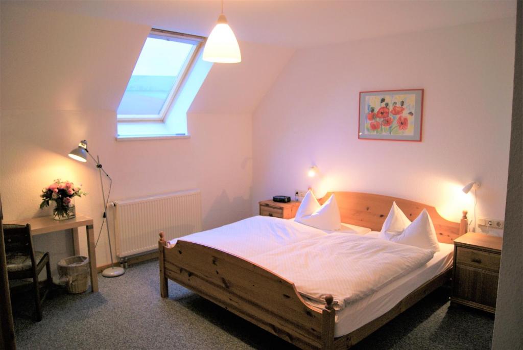 a bedroom with a bed with white sheets and a window at Pension Am Thieberg in Landolfshausen