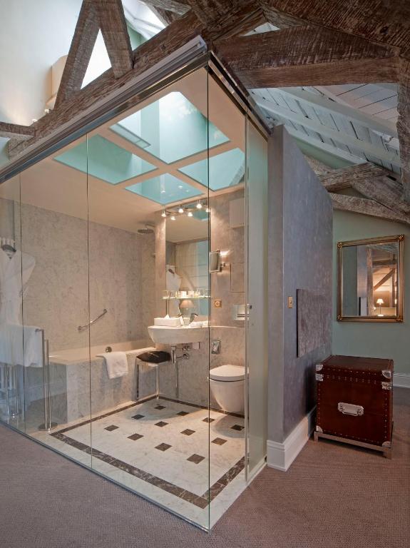 a bathroom with a glass shower and a sink at Hotel Le Place d'Armes - Relais & Châteaux in Luxembourg
