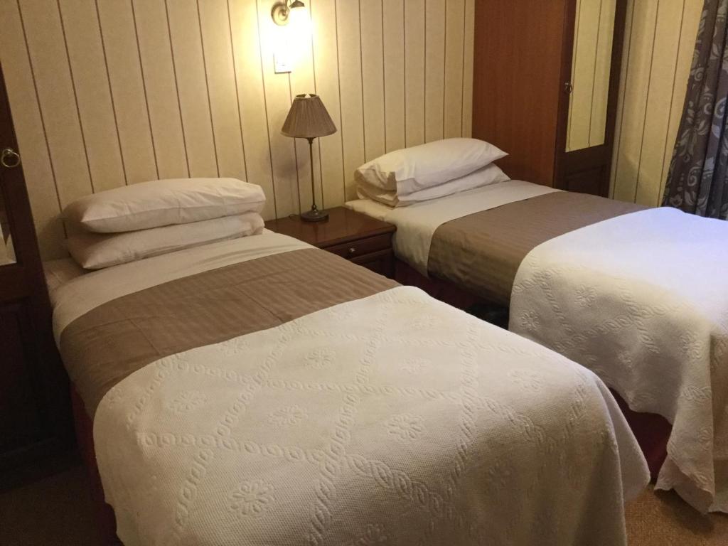 una habitación de hotel con 2 camas y una lámpara en The Old Inn, en Gairloch
