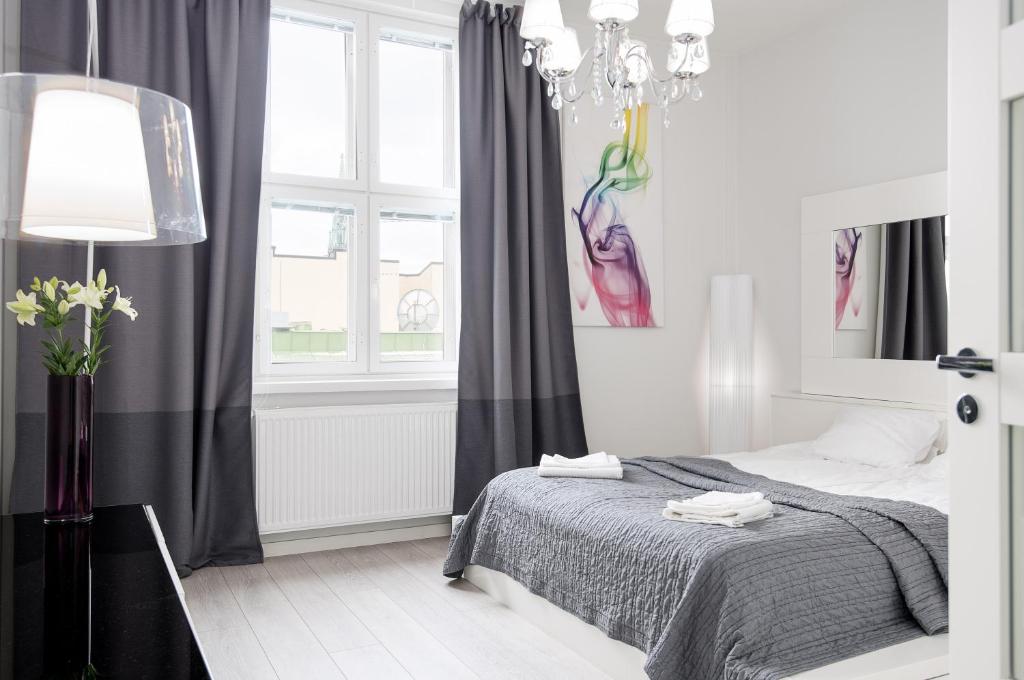 a white bedroom with a bed and a chandelier at New Modern Top Floor Residence in Helsinki
