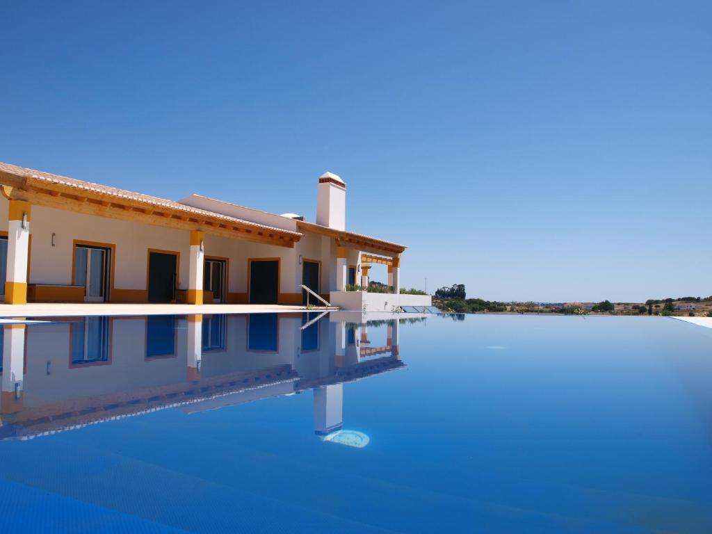 uma casa com uma piscina em frente em Herdade dos Montes Bastos em Santa Luzia