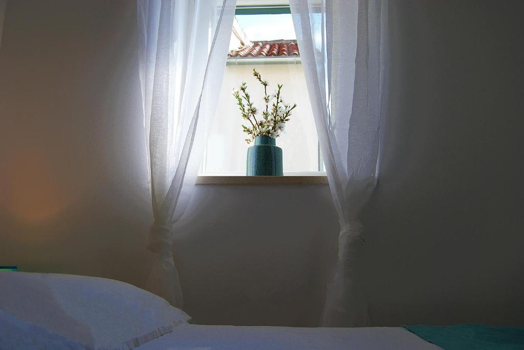 a bedroom with a window with a vase with flowers in it at Apartments Vidilica in Split