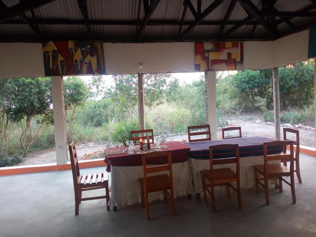 a table and chairs in a room with a large window at The Elephant Home in Katunguru
