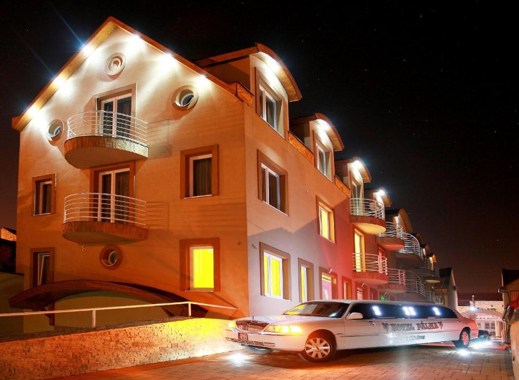 尼爾巴托爾的住宿－Hotel Pálma，夜间停在大楼前的汽车
