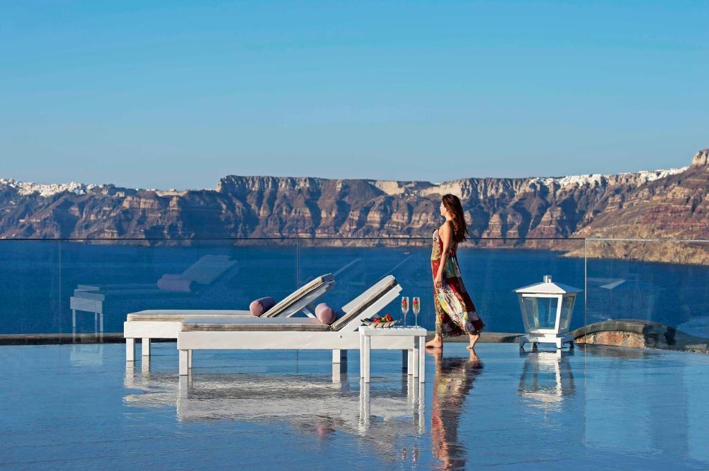 een vrouw die midden in het water loopt bij Acroterra Rosa Luxury Suites & Spa in Akrotiri