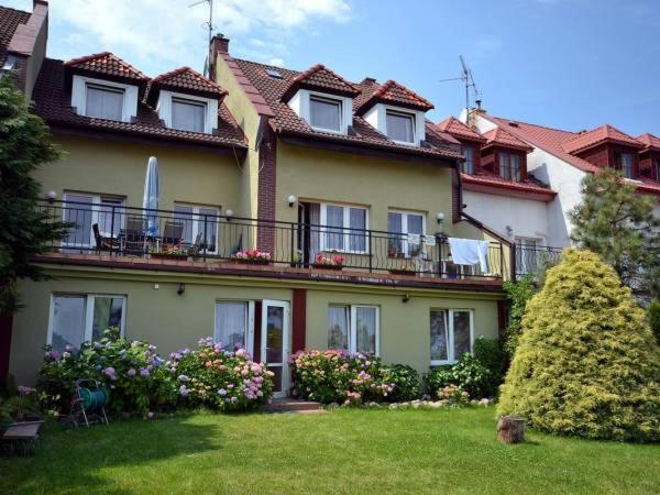 a large yellow house with a balcony and a yard at SunRise Mielno in Mielno