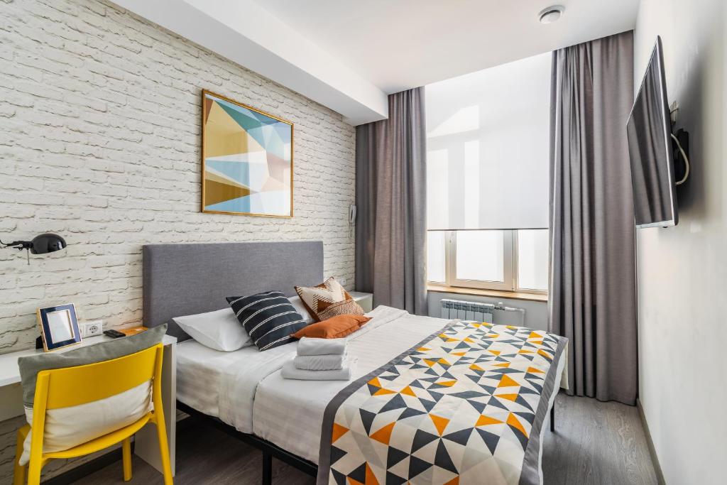 a bedroom with a bed and a yellow chair at Trend Samara in Samara