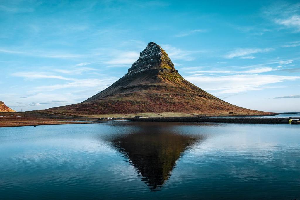 Kirkjufell Hotel by Snæfellsnes Peninsula West Iceland - Grundarfjordur في غروندافيوردور: جلسه جبليه بجانب تجمع المياه