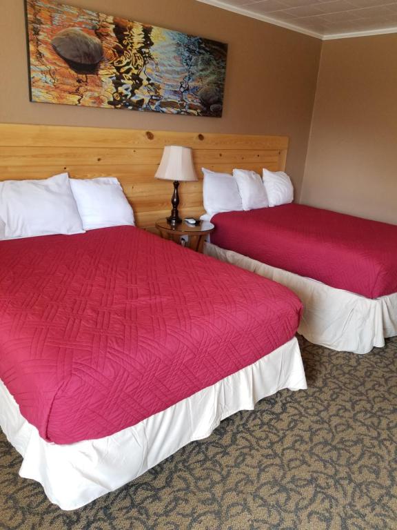 Eunice的住宿－L'Acadie Inn & RV Park，红色床罩的酒店客房内的两张床