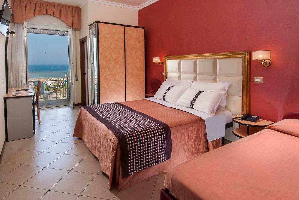 リミニにあるHotel Heliosのベッド2台とバルコニーが備わるホテルルームです。