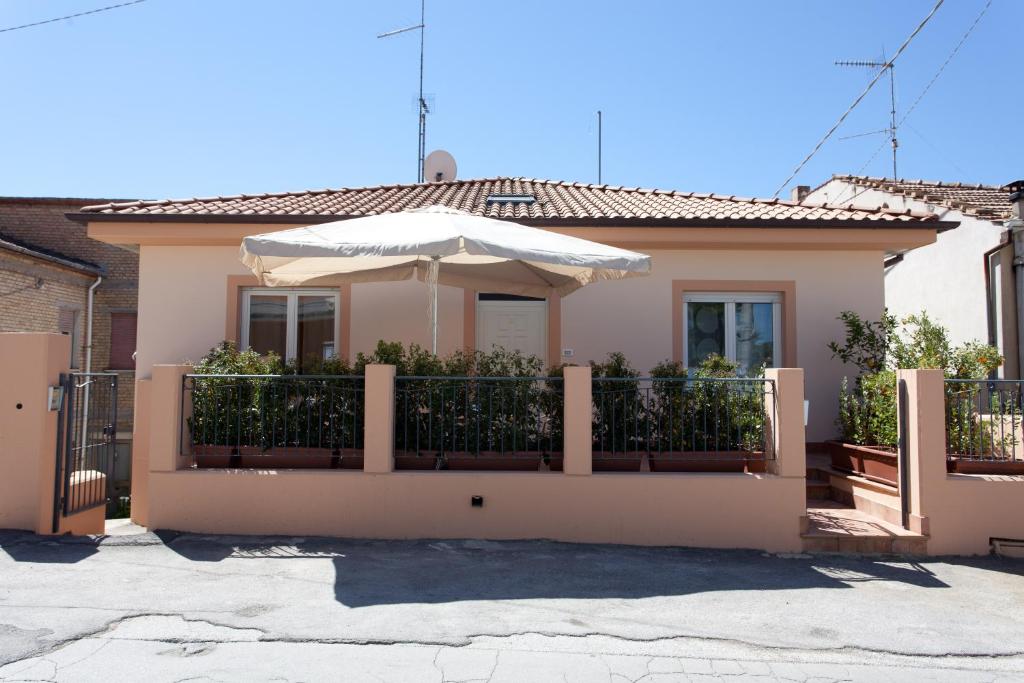 a house with a fence and an umbrella at B&B I Poeti in Collecorvino