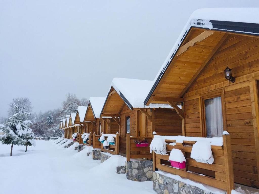 a row of wooden cabins in the snow at Villas Jezerca in Valbonë