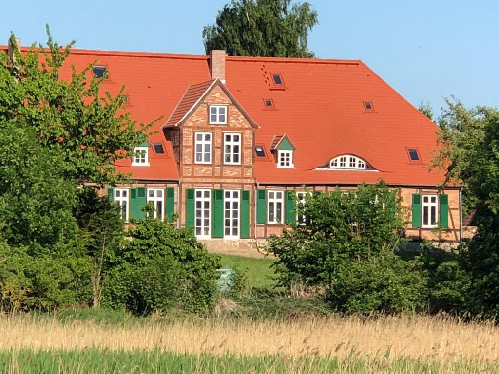 a large house with an orange and green roof at Gutshaus Redentin in Krusenhagen