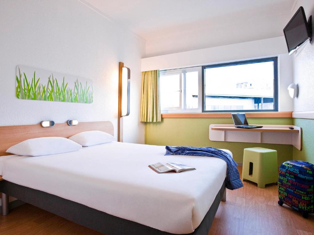 Un dormitorio con una gran cama blanca y una ventana en ibis budget Parauapebas en Parauapebas