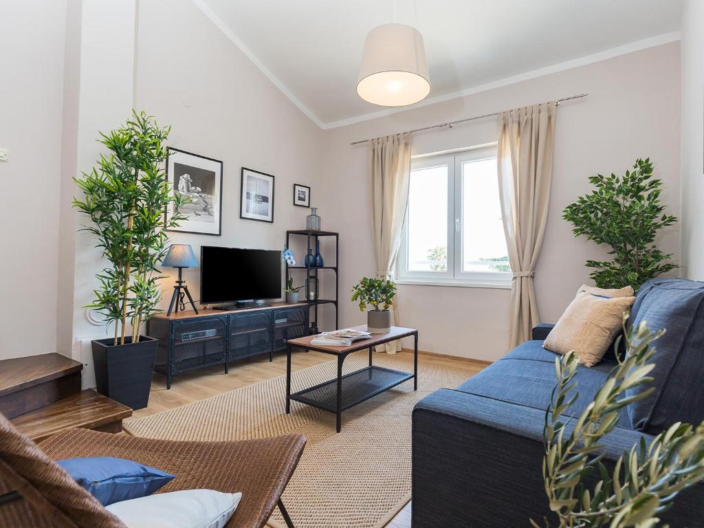 a living room with a blue couch and a tv at New City Center Design Apartment in Poreč