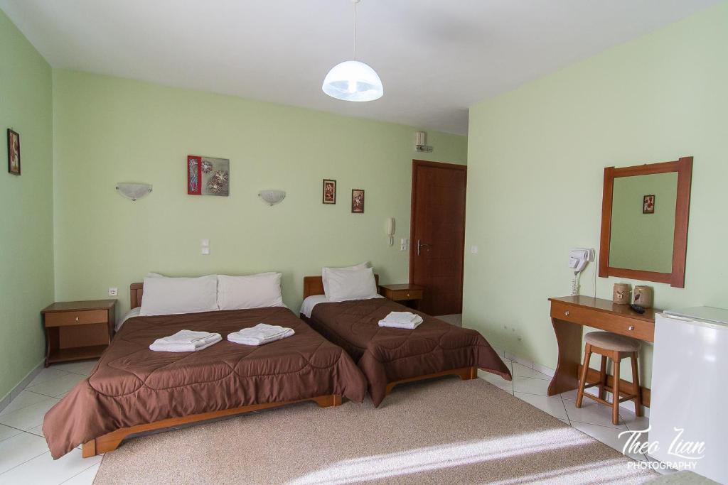 1 dormitorio con 2 camas, escritorio y espejo en Orama Rooms, en Ioannina