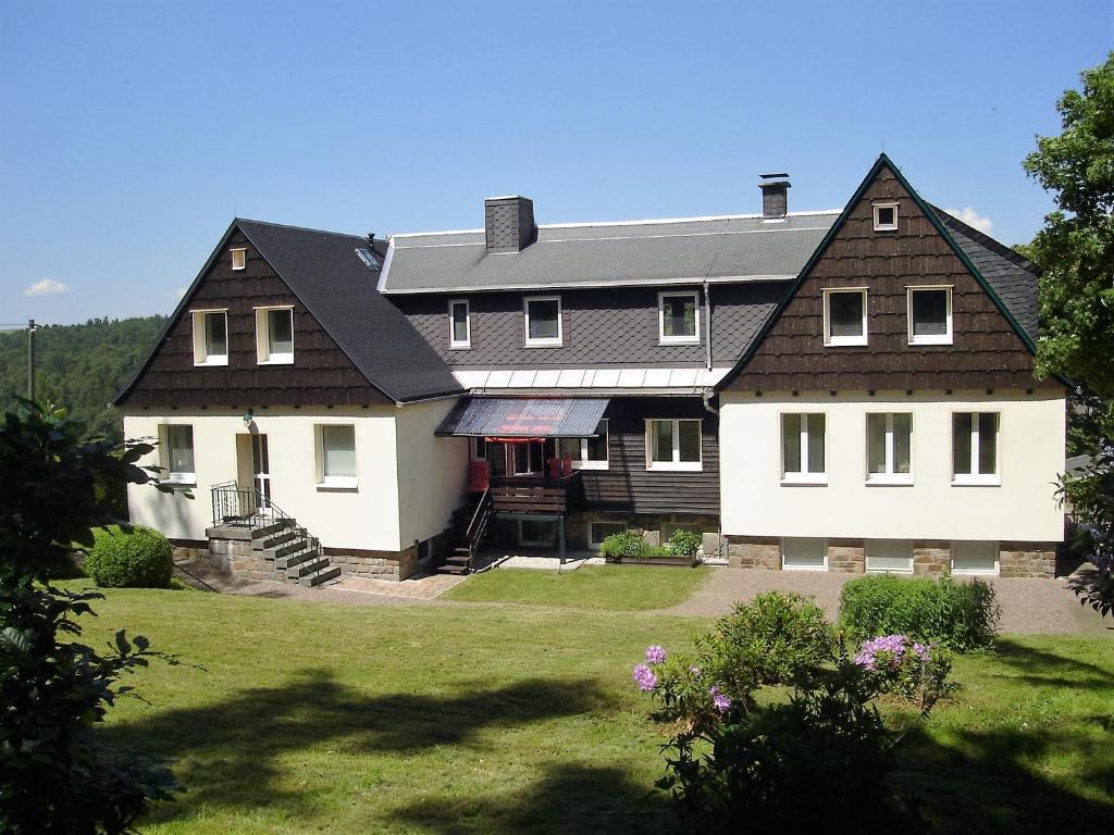 uma grande casa branca com um telhado preto em Ferienwohnung Goldene Höhe em Rechenberg-Bienenmühle