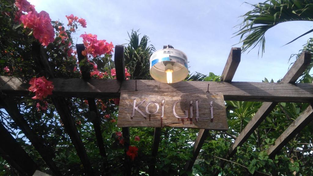 un cartel en una valla de madera con una luz en ella en Koi Gili Guest House, en Gili Trawangan