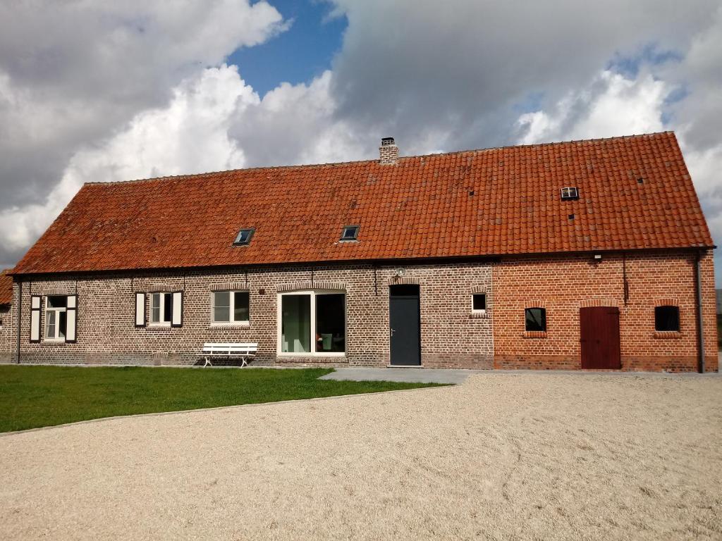 a large brick building with a red roof at Hauwaertshoeve in Beernem
