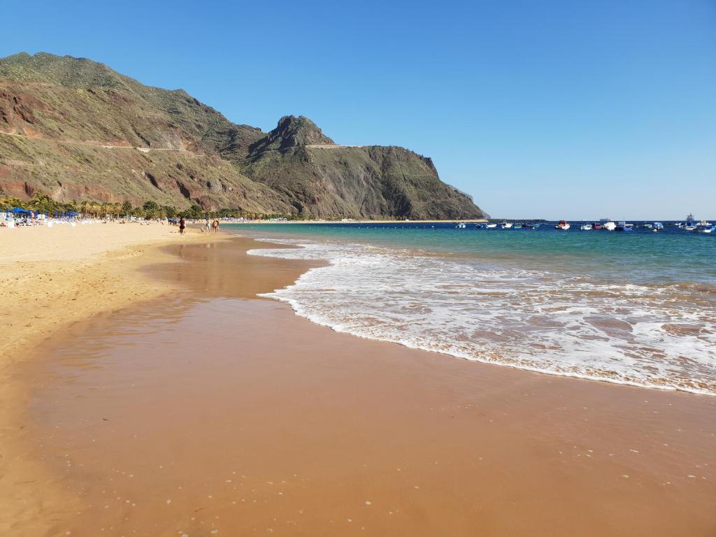 a beach with people walking on the sand and the ocean at Las Teresitas Apartment in San Andrés