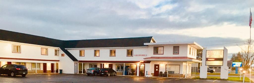 un edificio blanco con coches estacionados frente a él en North Country American Inn, en Kalkaska