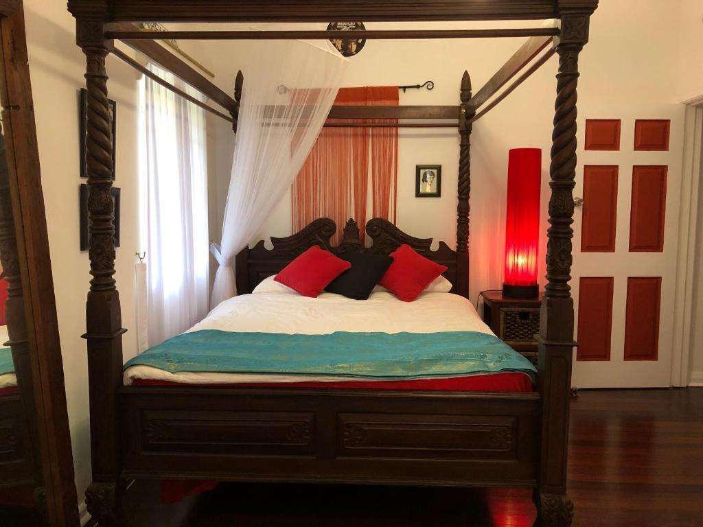 a bedroom with a canopy bed with red pillows at Island Time Guest Room in Flying Fish Cove