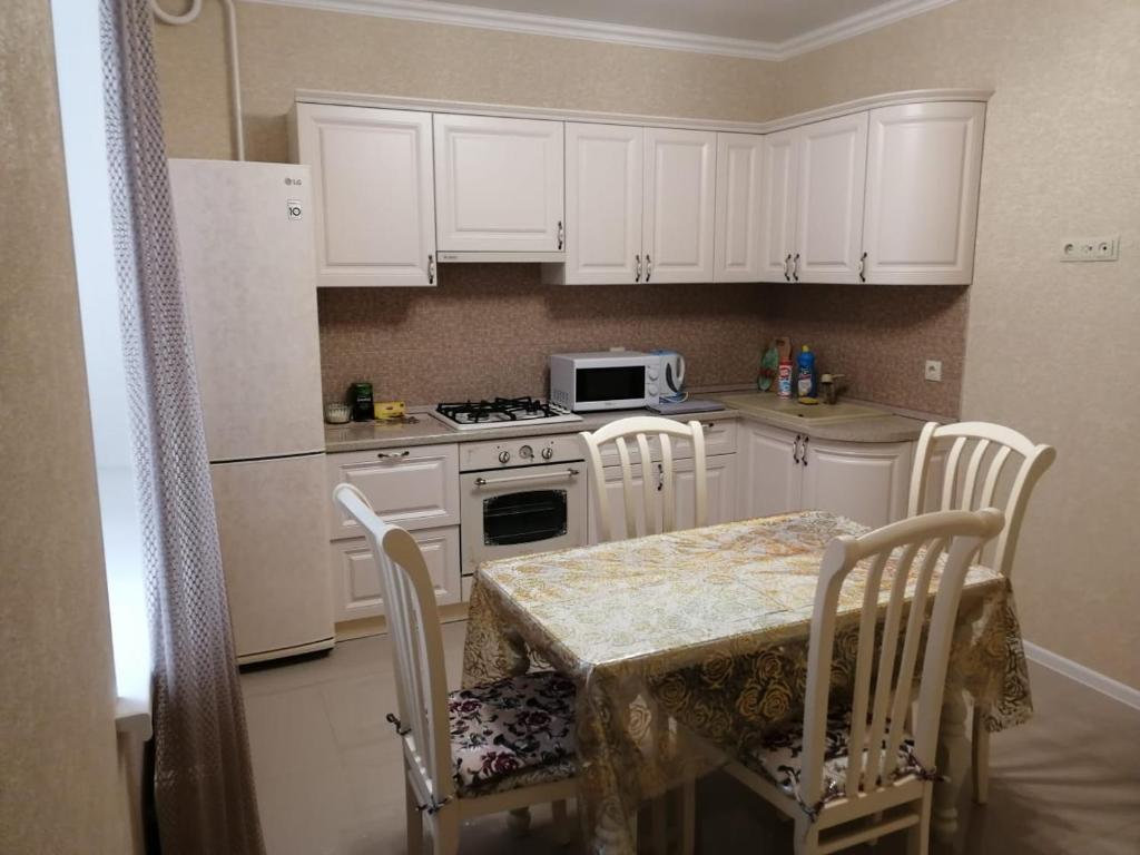 kuchnia z białymi szafkami i stołem z krzesłami w obiekcie Апартаменты, Московская 97 w mieście Piatigorsk
