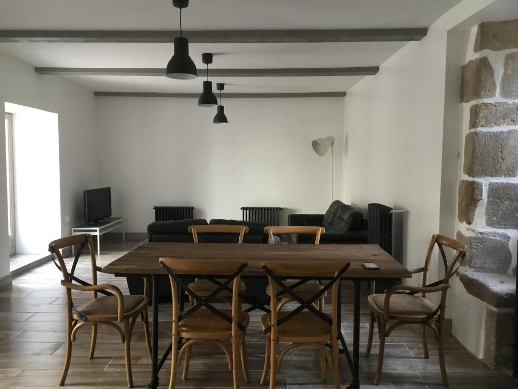 ein Esszimmer mit einem Holztisch und Stühlen in der Unterkunft Maison de bourg avec cour privée in Tallende