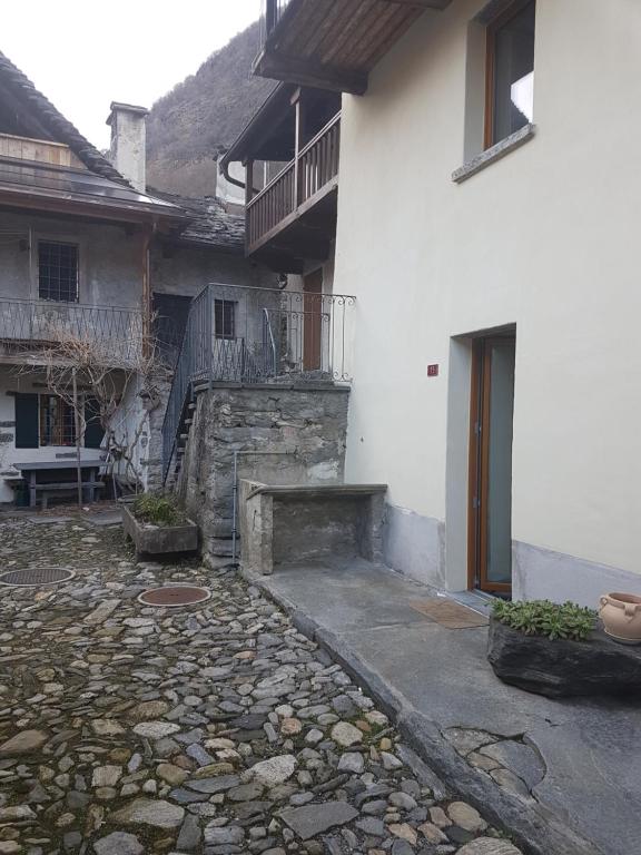 a white building with a stone walkway next to a building at Casa Antica Corte in Giumaglio