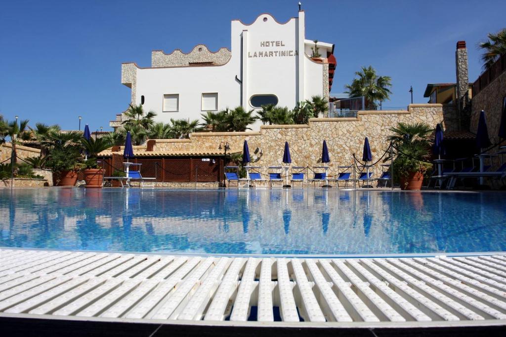 uma grande piscina com cadeiras e um edifício em Hotel La Martinica em Ficarazzi