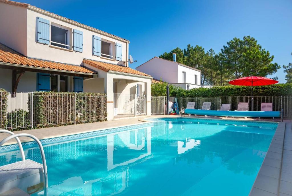 una piscina con sombrilla y una casa en Le Pavot en La Tranche-sur-Mer