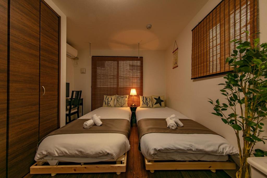 two twin beds in a room with a lamp at Apartment Heights HANA in Sakai