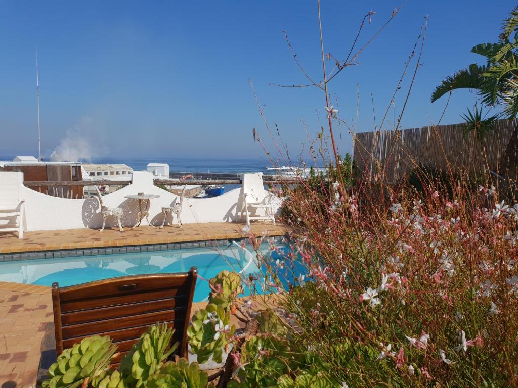 a pool with a bench and the ocean in the background at Courtyard@Saxon in Gansbaai