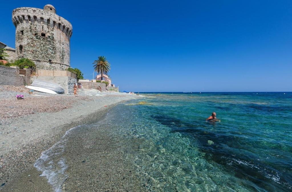 a person swimming in the water next to a castle at Appartement vue sur mer in Santa-Maria-di-Lota