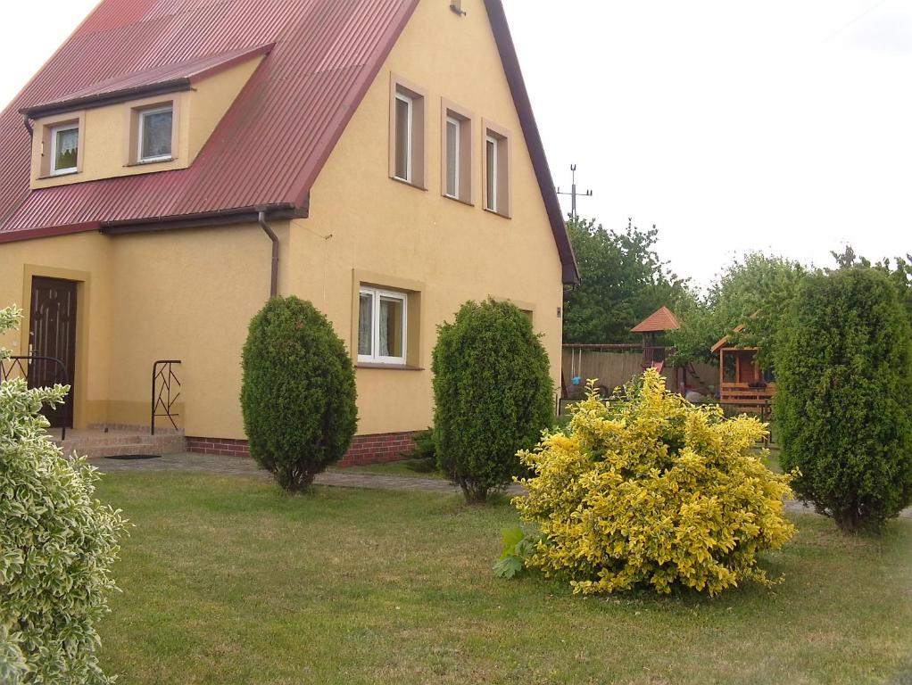 a house with a red roof and some bushes at Pokoje Stefania in Międzyzdroje