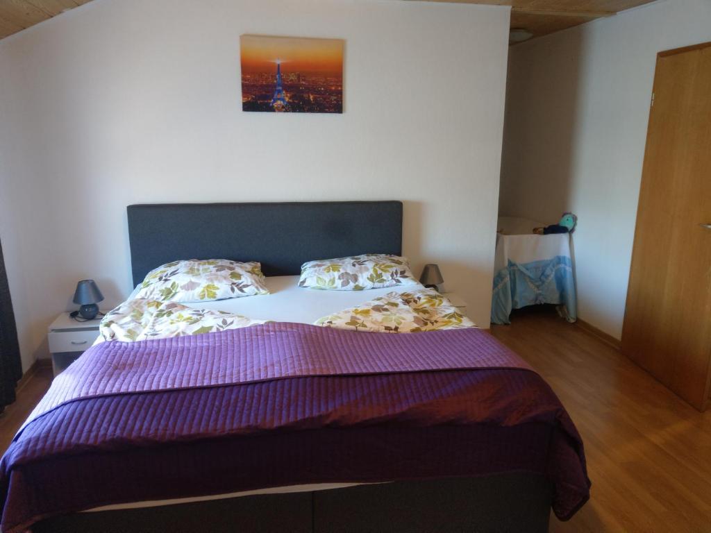 a bedroom with a large bed with a purple comforter at Meiks Ferienwohnung in Erfde