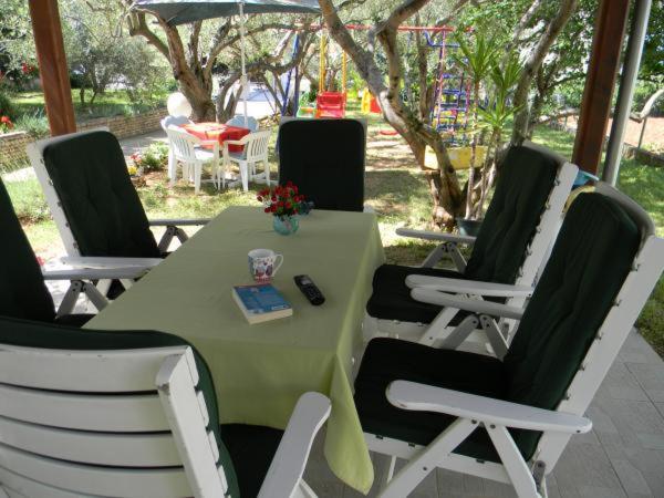 einem grünen Tisch mit Stühlen und einer Fernbedienung darauf in der Unterkunft Apartmani Maver in Sveti Filip i Jakov