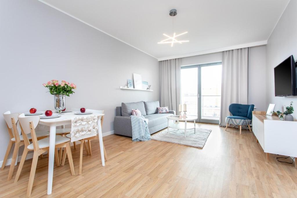 a white living room with a table and a couch at Seaside Beach 150m do Plaży - Praia Apartments - Polsat Plus Arena in Gdańsk